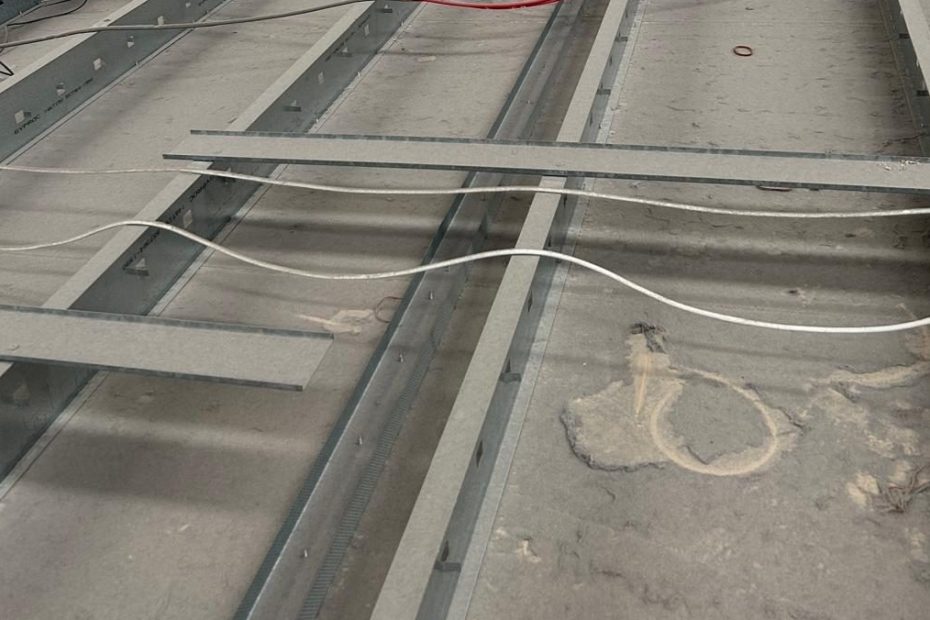 This image highlights the need for high access cleaning. The image shows the top of a suspended ceiling structure, possibly in a commercial or industrial building. The entire surface is heavily covered in dust, suggesting the area hasn’t been cleaned in a while. it is not only unhygienic it is a clear fire hazard.